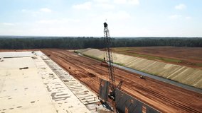 Drone video clip of a crane pulling up a concrete panel on a large construction site