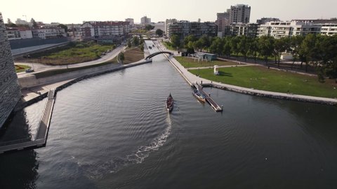 Cinematic aerial shot of a moliceiro boat travelling toward the narrow water canal in Aveiro.