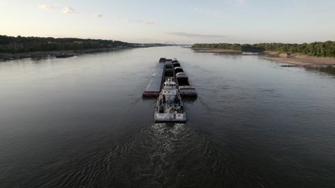 Aerial descent behind tugboat pushing barges on Mississippi River, St. Louis.