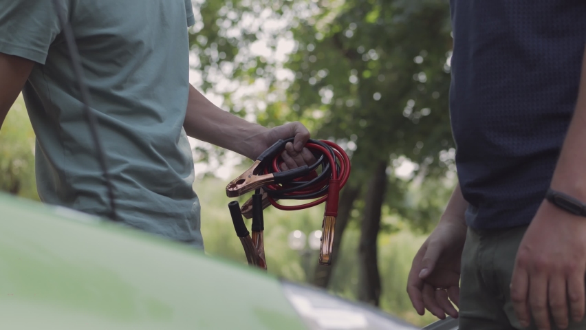 Close-up, a motorist thanks a friend for his help in repairing a car and shakes his hand,