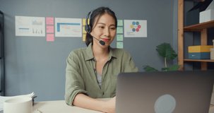 Asia businesswoman using laptop talk to colleagues about plan in video call while work from house at living room. Customer service agents or call center, social distancing, quarantine for coronavirus.