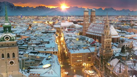 Germany Munich skyline aerial view at winter with snow, fly over munich marienplatz sqaure frauenkirche town hall in old town city centre in bachround alps mountains at sunrise.