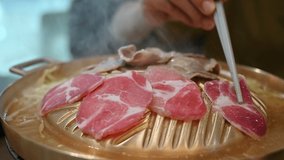 Footage video of customer cooking smoke grilled Korean BBQ on iron grill pan. Korean BBQ is the popular method of grilling meat right at the dining table.