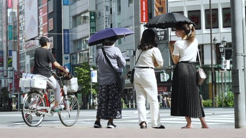 Tokyo , Japan - 08 03 2021: Pedestrians cross a busy road in Tokyo, Japan