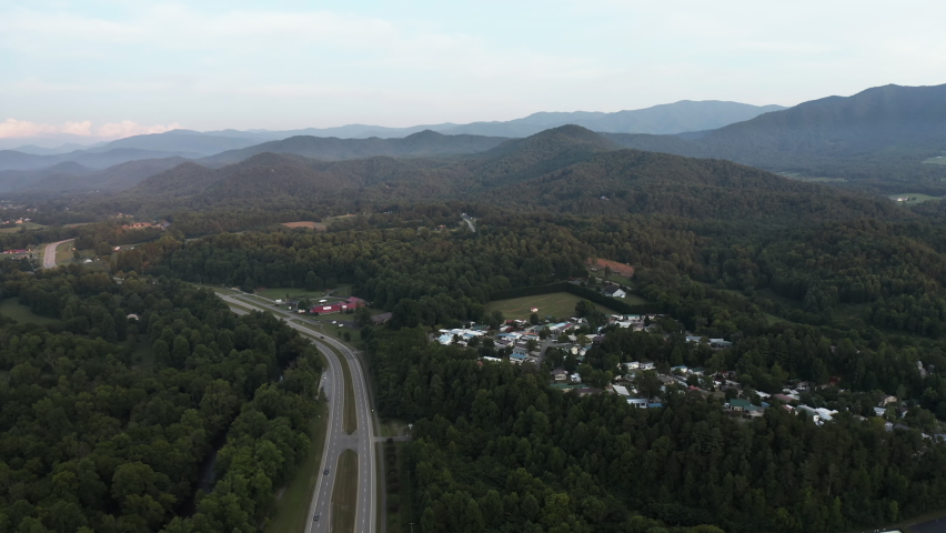 Aerial above Great Smoky Mountains in Tennessee, United States. Two lane road leading to high mountains near Townsend. Late afternoon light
