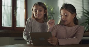 Authentic Shot of Two Little Girls Watching Kids Song on Digital Tablet, Singing Along and Dancing to it. Two Sisters in the Kitchen Enjoying Spending Weekend Together. Being Active, Using Technology 