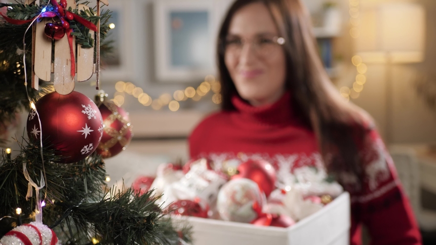 Woman with Christmas toys. Happy attractive woman holding box with Christmas toys in her hands and smiling. Slow motion
