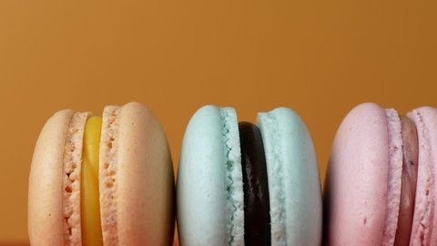 Multicolor Macarons, French macaroon, sweet tasty desserts. Isolated on a yellow background.