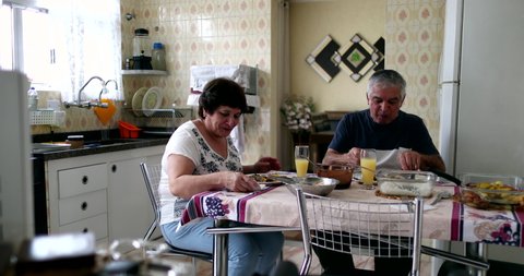 Older couple eating lunch at home kitchen
