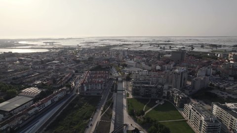 Sprawling cityscape. Ria de Aveiro urban canals towards lagoon. Aerial pullback 