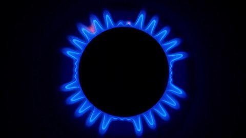 Gas stove burner. Turn on a gas burner in the dark. Kitchen cooktop, the blue flame of natural gas. View from the top.