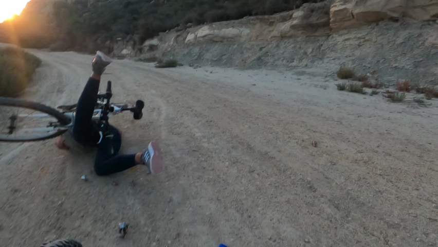 Young girl riding her bike through a dirt road trip over a pothole, and feels down doing a front flip. Afterward, she is attended and helped by the person recording with the camera. | Shutterstock HD Video #1079895848