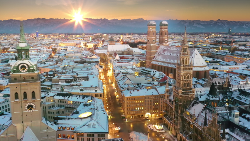 Beautiful sunset over Munich skyline aerial view. Munich frauenkirche, old town view, cathedral and marienplatz birds view from sky. Munchen winter aerial view with snow alps mountains. Royalty-Free Stock Footage #1079897540