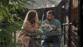 Attractive young couple having lunch sitting at cafe table outdoors, drinking coffee and talking. Woman and man drinking coffee on the street in a cafe - Powered by Shutterstock - Get 15% off with code: PIKWIZARD15
