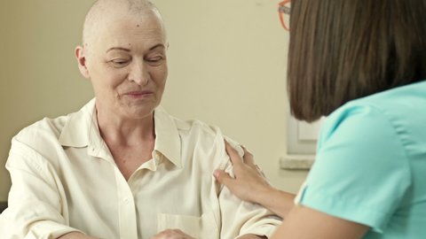 Female oncologist is trying to cheer up an elderly woman with cancer. Life extension hope.