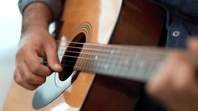 Lifestyle concept. Close up hands Young asian musician playing guitar in living room at home on this weekend. Relaxing with song and music. Asian man having fun playing acoustic guitar