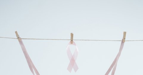 Animation of bra and ribbon hanging on wire on white background. breast cancer positive awareness campaign concept digitally generated video.