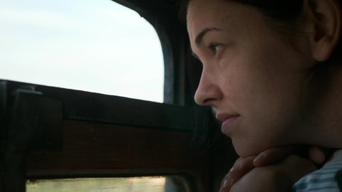 Thoughtful Woman Look out of Train Window while Traveling by Railway. Female Tourist Lying on Top Bunk Bed Shelf on Old Vintage Third 3rd Class Platzkart Car 4K