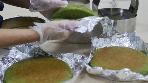 a woman pastry chef checks the readiness of green spinach biscuits in tin foil tins. Slow motion. Diet spinach cake.