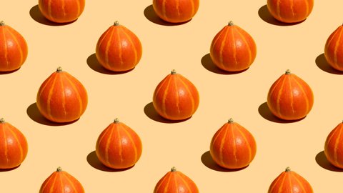 Stop motion animation Many ripe autumn orange pumpkins for Thanksgiving and Halloween in a seamless pattern on a beige background will randomly shrink and enlarge like a button press. Seamless video