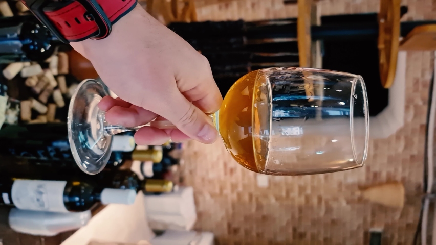 Slow motion POV male hand holding glass of wine with background of wine market.
