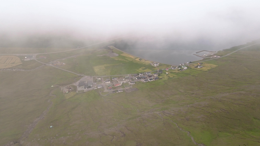 Beautiful aerial view of the town of Miovagur in the Faroe Islands, with its :churchs, grass roofs and colorful Houses in front of the ocean	