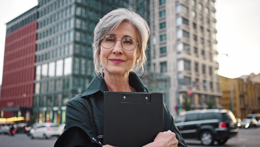 Equal rights, independent, proud woman concept Portrait of a mature woman on an urban background with a folder with documents in her hands. Slow motion. Royalty-Free Stock Footage #1079925563