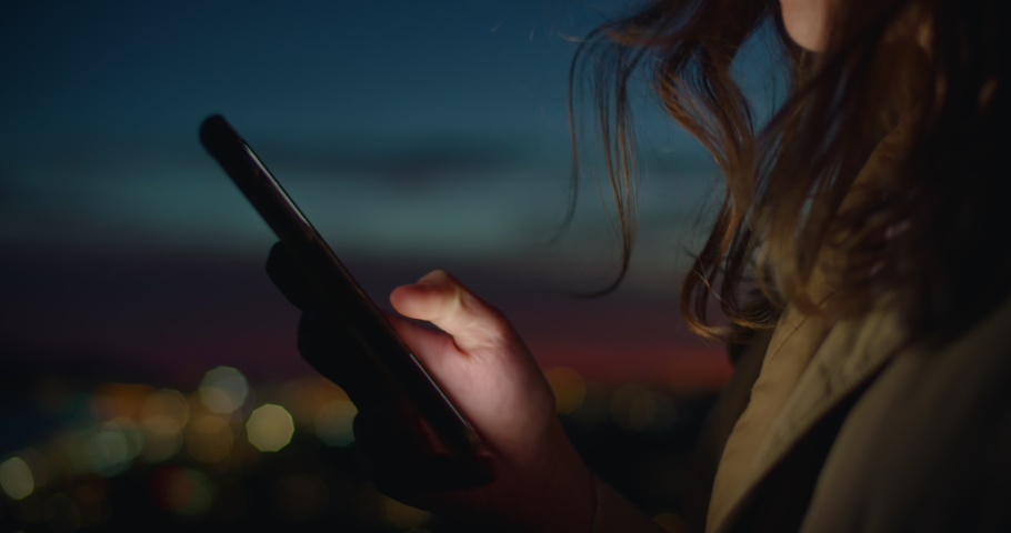 Close up on person use smartphone in sunset on street. Millennial generation z female scroll through news feed on app on her phone. Cinematic film look photo of pretty woman at sunset use phone Royalty-Free Stock Footage #1079925620