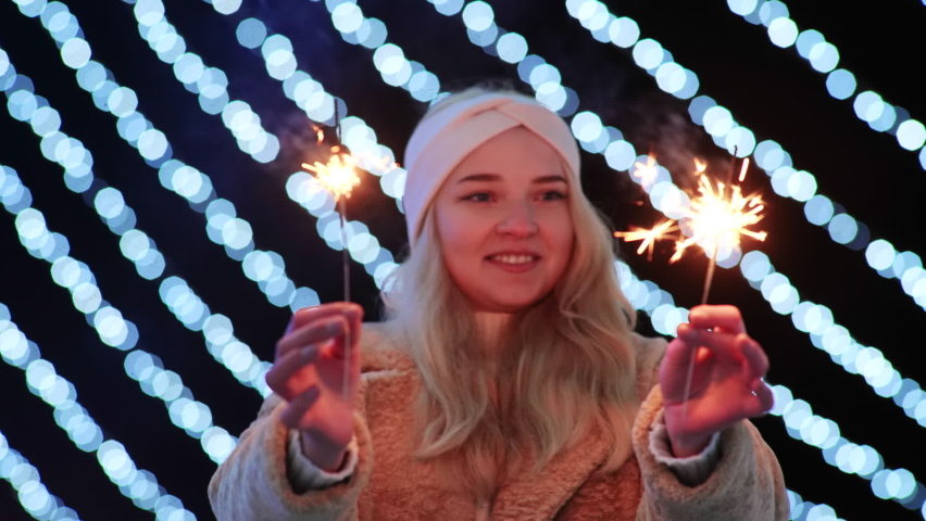 Girl with sparklers on the background of the Christmas lights of the evening city.