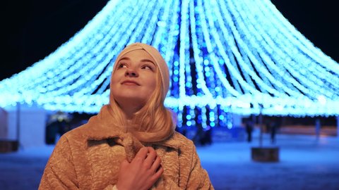 The girl admires the Christmas illumination in the evening city.