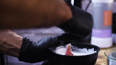 barbershop hairdresser mixes hair dye in a special container for hair dyeing white paint hairdresser's brush preparation for hair dyeing