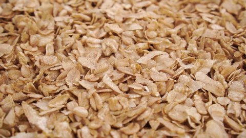 Dry wheat spelt flakes. Falling uncooked breakfast cereal in slow motion. Close up. Rotation