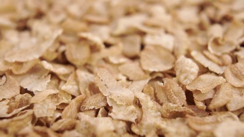 Wheat spelt flakes. Dry cereal healthy breakfast. Falling in slow motion. Rotation.