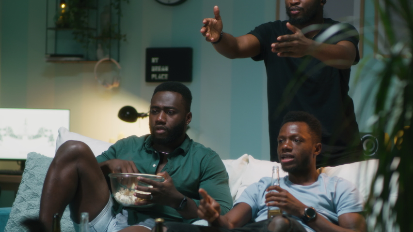 Nervous African American men with popcorn and beer watching match on TV then screaming and celebrating goal together in weekend evening in living room at home | Shutterstock HD Video #1079941781
