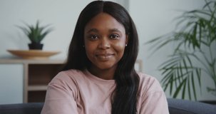Beautiful young african american woman with long straight hair looks straight into the camera and smiles, close-up portrait video