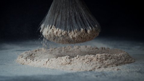The fluffy brush hits a mountain of face powder. Advertising of cosmetics. Decorative cosmetics for the face. Powder texture.
