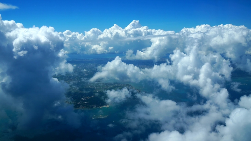 View from an airplane flying in Okinawa surrounded by beautiful coral reefs and many cumulonimbus clouds that are typical of tropical countries Royalty-Free Stock Footage #1079948969