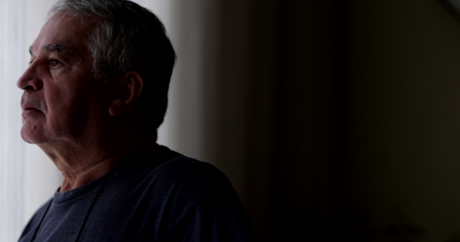 Contemplative senior looking through window. Pensive thoughtful older man