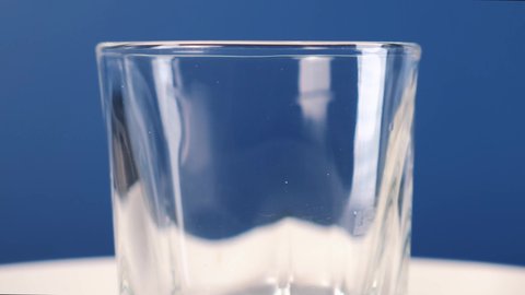 Pouring cola into a glass on a blue background. Static frame. 4k footage.