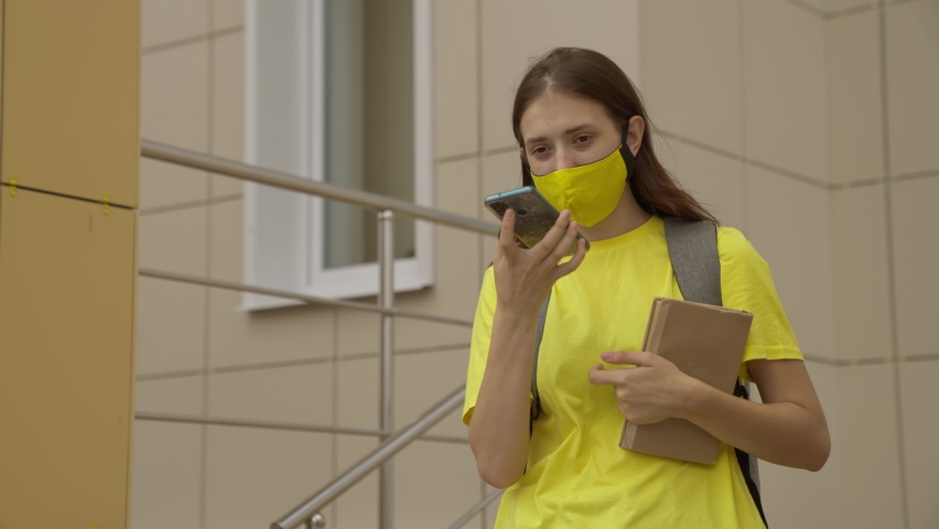 Schoolgirl girl in a mask with a backpack talks on a smartphone online, modern trends in technological progress, protect herself from coronavirus infection, air filtration Royalty-Free Stock Footage #1079951060