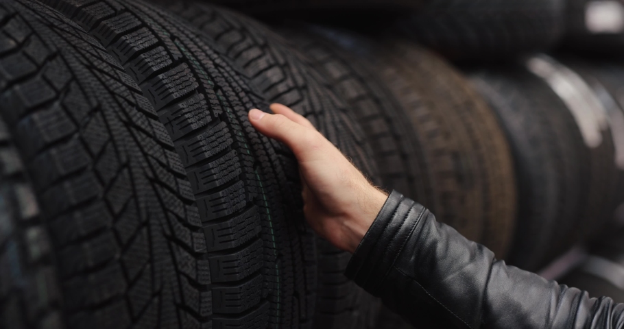 Man chooses and touches protector of winter car tires in the auto shop Royalty-Free Stock Footage #1079954117