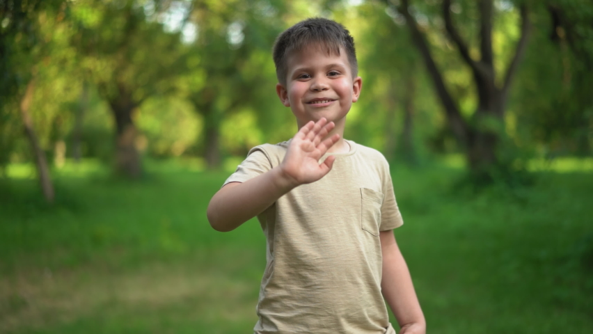 Child Smiles With an Antistress Toy and Takes Step Back. Slow Motion Video of Child Walking Away with toy in Hand. Kid Holding Rainbow Pop It Fidget Toy. High quality 4k footage