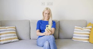 Woman sitting on couch having video call on her smartphone
