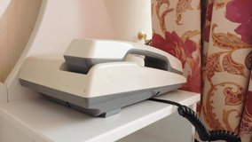 4k video, retro push-button telephone in a classic hotel room. An incoming phone call to a landline phone, a woman picks up the phone