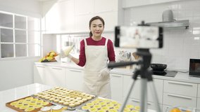 4K Asian woman bakery shop owner using smartphone with internet presentation sweet dessert bakery on social media in the kitchen. Small business entrepreneur and online marketing food delivery concept