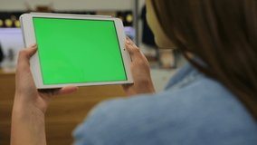 young beautiful woman watching video on tablet with green screen in the cafe close