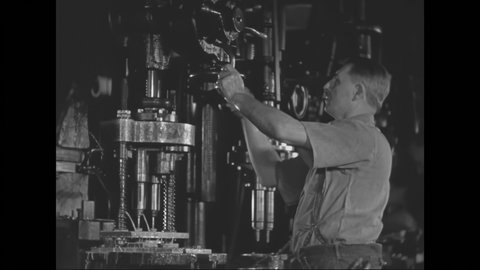 1930s: Worker places axle into drill press and lowers the drill. Worker removes axle and finishes piece on floor. Worker turns wheels to lower press. Worker goes to second station to work.