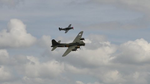 Duxford UK JULY, 11, 2015 US Airforce Bomb Airplane of World War II Boeing B-17 Flying Fortress Sally B in Flight during an Airshow with a North American P-51 Mustang Fighter Aircraft 4K