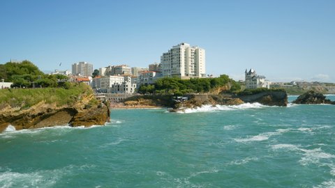 The coastline of the famous Biarritz in summer (Aquitaine, France), with atlantic ocean waves crushing on the beautiful cliffs. Turquoise waters in the foreground. Blue sky in the background.