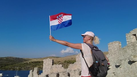 SLOW MOTION: Woman waving a Croatian flag on top of Wall of Ostrica. Also called CHINESE WALL or Bedem Grebastica defensive wall. Grebastica village in Sibenik-Knin County of Croatia in Dalmatia.